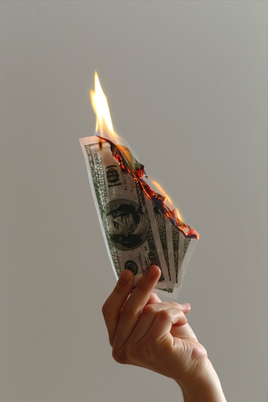Jp Valery en Unsplash, mano sosteniendo billetes quemándose